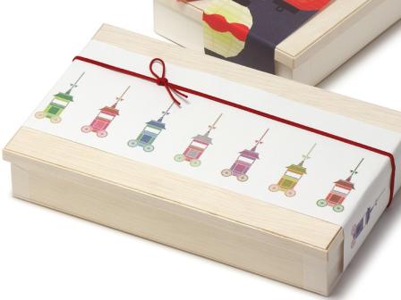 折箱：00-11123-405 Kウッド 1.5合 かぶせ蓋付、帯紙：07-15302-380 帯紙 山鉾巡行、飾りゴム：00-17403-526 彩宝ゴム からくれない 16cm を組み合わせたイメージ