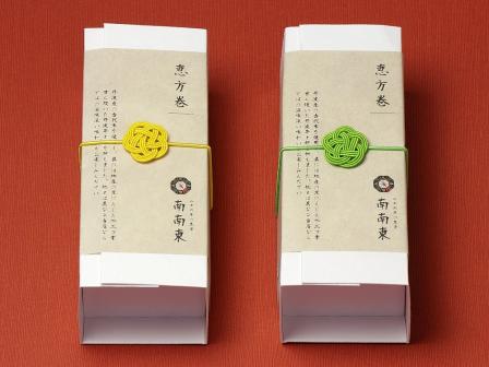容器:07-15113-014 紙のうつわ 至白 恵方巻ハーフ ワンタッチ、掛紙:07-18801-175 OA和紙 麻布 A4(薄)、ゴム:07-17403-074 水引飾りゴム ミニ梅むすび 黄・07-17403-064 水引飾りゴム ミニ梅むすび 若草 を使用したラッピング例