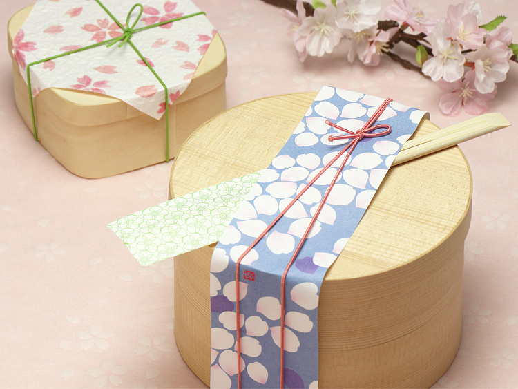 お花見弁当に似合う組み合わせのご提案【使用アイテム】（手前）曲わっぱ：経木曲物 丸型2段140φ、、帯紙：帯紙 はな筏、飾りゴム：花むすびゴム 紅梅（こうばい）12cm、箸：割箸 竹天削先細21cm HANA５色 箸袋セット（奥）容器：白楊 角丸折、掛紙：越前の和紙 もみ紙 10角 春 袋入、飾りゴム：彩宝ゴム うぐいす 12cm、造花：造花 桜バンチ３本セット ツートンピンク